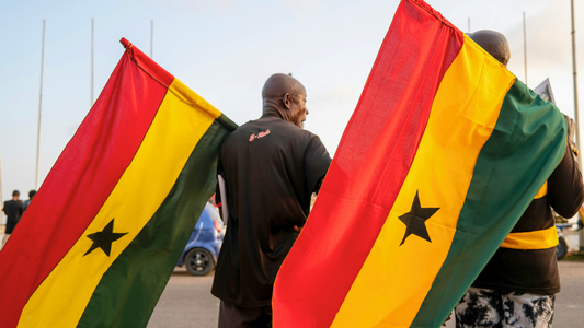 Two men carrying Ghanian Flags in a street parade