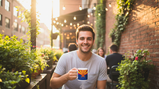 Young man sitting outside at a café drinking coffee out of an Arizona flag coffee mug