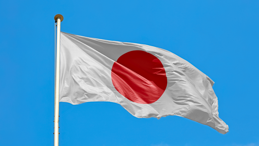 Japan's Hinomaru (circle of the sun), with its white background and red circle flag flying proudly against a blue sky.