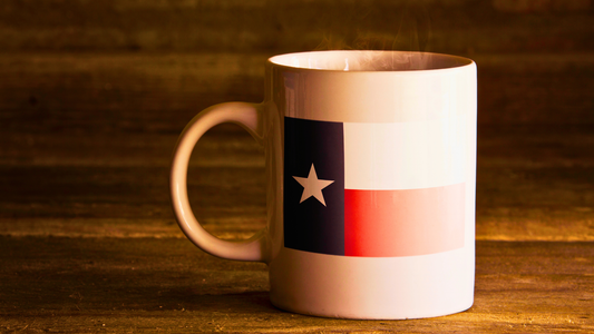 Coffee mug with the Texas state flag printed on, shot on a wooden coffee table with natural light shining through