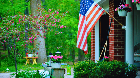 An American flag outside a country home on a flag pole.