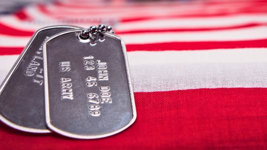 US Army dog tags laying on a US Flag with the red and white stripes visible