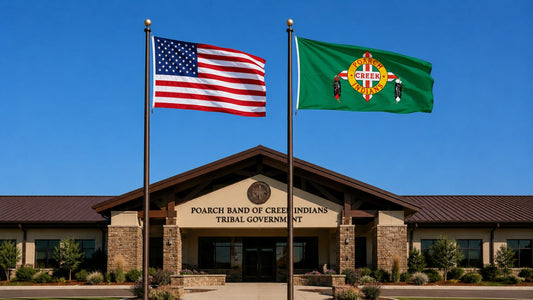 A Poarch Band of Creek Indians Flag flying next to the US flag in front of a government building