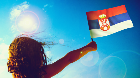 A girl seen from behind, waving a small Siberian flag on a sunny day with blue skies