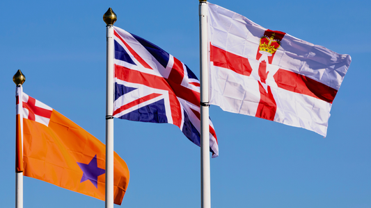 Three flags representing Northern Ireland flying in the wind - The Orange Order, The Union Jack and The Northern Ireland Ulster Banner