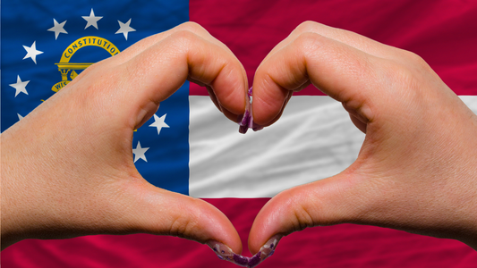 Woman making a heart shape with her hands in front of a Georgia State Flag