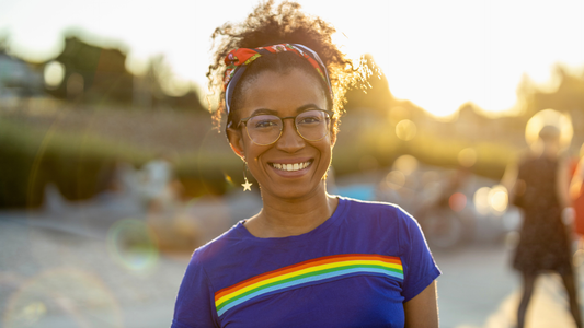 Woman standing outside wearing a blue t-shirt with the pride flag printed on